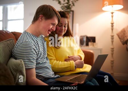 Junge Abstiegsyndrom Paar sitzt auf einem Sofa mit Laptop zu Hause Stockfoto