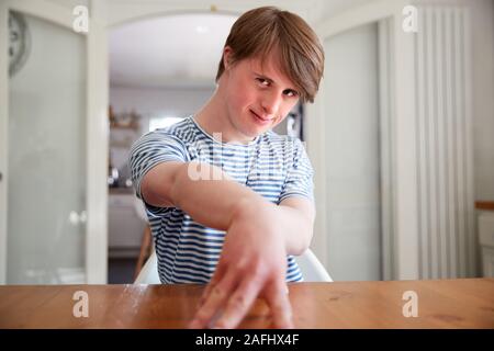 Porträt der jungen Abstiegsyndrom Mann sitzt am Tisch in der Küche Stockfoto
