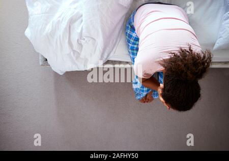 Ansicht der Frau tragen Schlafanzug mit Depression sitzen auf dem Bett zu Hause Leiden Stockfoto