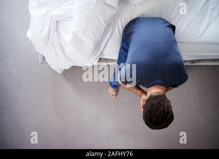 Draufsicht der Mann mit Schlafanzug mit Depression sitzen auf dem Bett zu Hause Leiden Stockfoto