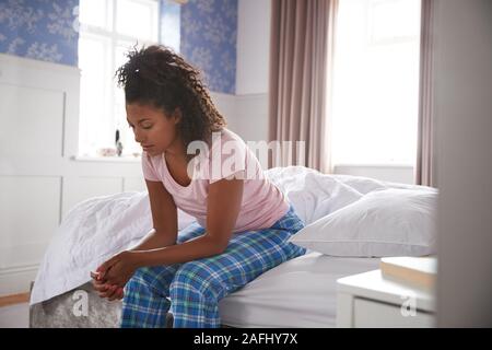 Frau mit Schlafanzug mit Depression sitzen auf dem Bett zu Hause Leiden Stockfoto