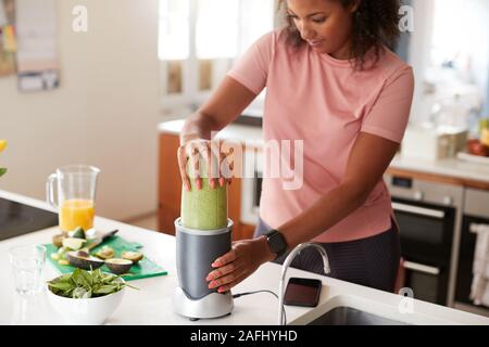 Frau, die Gesunden Saft trinken mit frischen Zutaten in elektrische Saftpresse Nach Übung Stockfoto