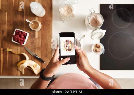 Overhead Shot der Frau unter Bild des gesunden Frühstück auf Handy zu Hause nach dem Training Stockfoto