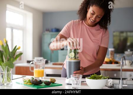 Frau, die Gesunden Saft trinken mit frischen Zutaten in elektrische Saftpresse Nach Übung Stockfoto