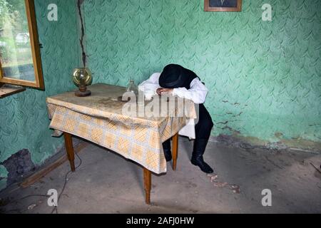 Ivanovo, Serbien, 15. April 2018. Ein einsamer Junge mit Hut ist allein sitzen an einem Tisch in einem Zimmer und denkt über sein Leben. Die Zimmer auch Wi Stockfoto