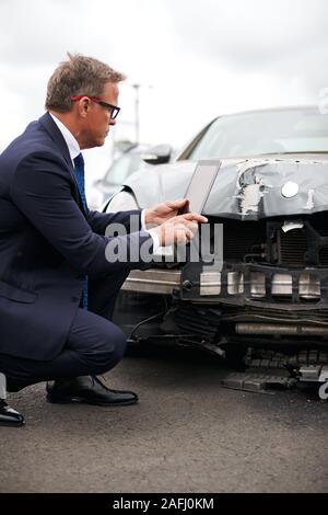 Männliche Insurance Loss Adjuster mit digitalen Tablet Inspektion Schaden an dem Auto von Motor Unfall Stockfoto