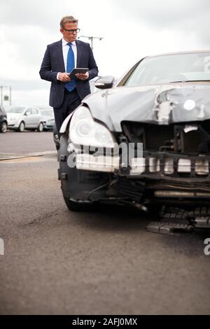 Männliche Insurance Loss Adjuster mit digitalen Tablet Inspektion Schaden an dem Auto von Motor Unfall Stockfoto