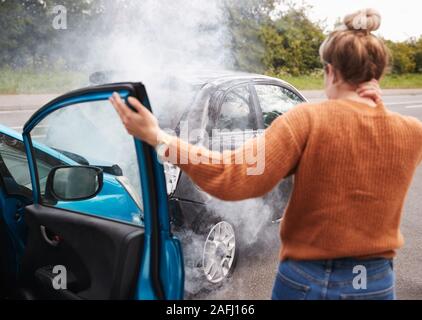 Ansicht der Rückseite des Weiblichen Kraftfahrer mit Kopfverletzung Aussteigen aus dem Auto nach einem Crash Stockfoto