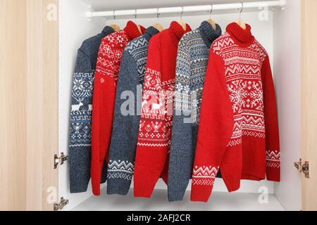 Verschiedene gestrickt Weihnachten rollkragen pullover oder Pullis mit Nordic geometrische Verzierung auf Kleiderbügel im Schrank Rack Stockfoto