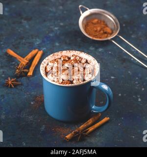 Heiße Schokolade mit Kakao bestreut mit Marshmallows auf einem blauen Tisch in einer blauen Schale. Weihnachten Winter trinken. Stockfoto
