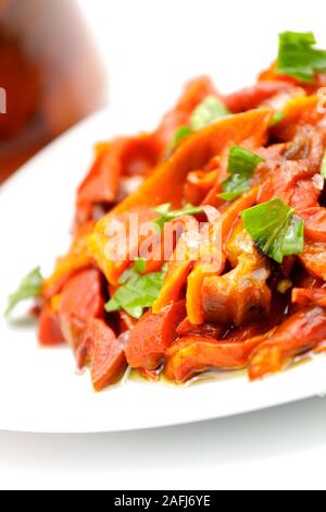 In Scheiben geschnitten eingelegte rote Paprika mit frischer Petersilie bestreut. selektive Fokus mit geringer Tiefenschärfe. Stockfoto