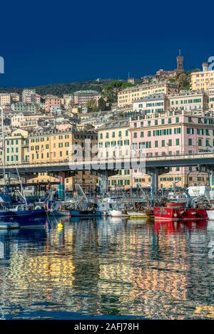 Bunte waterfront Gebäude im Hafen im Alten Hafen in Genua, Ligurien, Italien mit angelegten Boote unter einem sonnigen blauen Himmel in einem szenischen u wider Stockfoto
