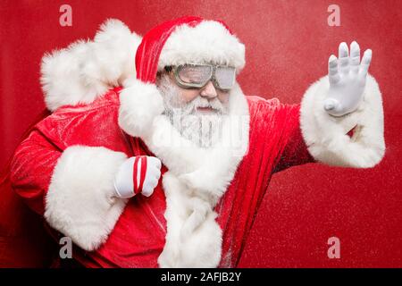 Profil Seite Foto von Konzentriertem ältere santa claus seine Hand halten Straße Problem im Schneesturm cataclysm Tragetasche sack Schutzbrille tragen Stockfoto