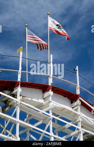 Amerikanische und kalifornische Flagge auf der Holzachterbahn Big Dipper im Santa Cruz Beach Boardwalk Amusement Park, Santa Cruz, Kalifornien, USA Stockfoto