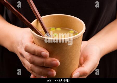 Frau Essen unterwegs. Miso Suppe im Takeaway Cup. Der traditionellen asiatischen Küche. Stockfoto