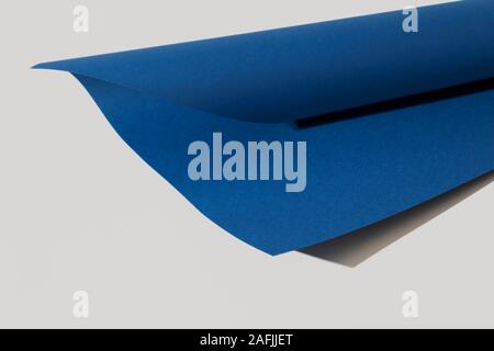 Ein Karton in trendigen Classic blau, die Farbe des Jahres 2020, auf einem weißen Hintergrund gerollt Stockfoto