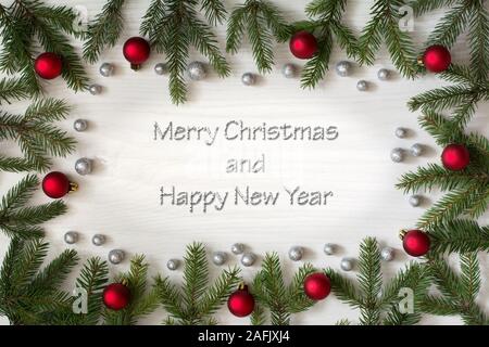 Weihnachtskarte mit Tannenbaum Äste, rote Kugeln und Brocade Globuli auf weißem Hintergrund Holz, tiefe Seite Schatten - Grüße Text Stockfoto