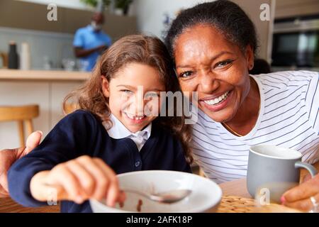 Portrait von Großeltern in der Küche mit Enkeltochter essen Frühstück, bevor Sie in die Schule gehen Stockfoto