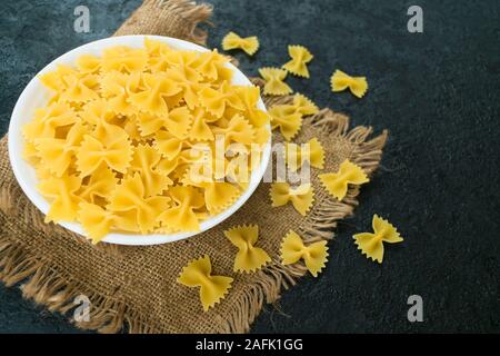 Nudeln in der Form eines Bogen in eine Platte auf einem schwarzen Hintergrund. Stockfoto