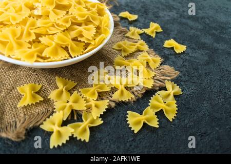 Nudeln in der Form eines Bogen in eine Platte auf einem schwarzen Hintergrund. Stockfoto