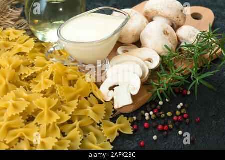 Zutaten für das Kochen von Nudeln mit Champignons in Sahnesauce auf schwarzem Hintergrund. Close-up. Stockfoto