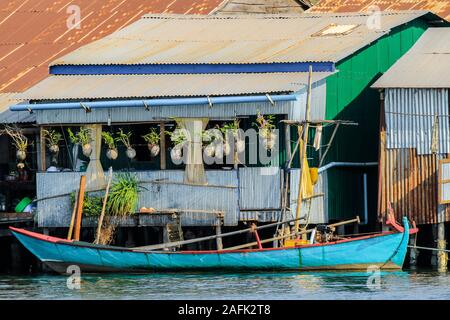 Boot von verzinktem Wellblech Pfahlbauten am Praek Chhu Tuek Fluss in diesem alten französischen kolonialen Fluss Hafen festgemacht; Kampot, Kambodscha Stockfoto