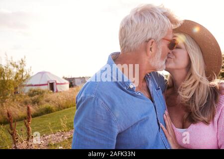 Liebevolle Reifes Paar in der Landschaft Küssen gegen das Abfackeln von Sun Stockfoto
