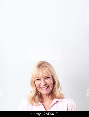 Studio Shot von lächelnden reife Frau gegen den weißen Hintergrund an Kamera Stockfoto