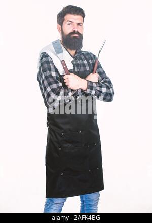 Grill Zubehör. Der bärtige Mann mit Grill Greifer tools. Hipster in Schürze mit Metallgegenstände, Grill. Grill kochen. Kochen Grill. Die Zubereitung von Speisen am Grill mit einem Grill. Stockfoto