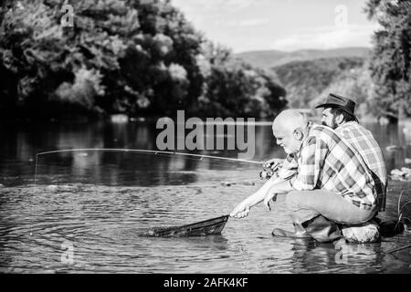 Wilderer angeln. Schwarzmarkt Kaviar. Die illegale Jagd Kaviar. Auszüge Eier vom Stör gefangen. Trap für Fische. Männer sitzen am Flußufer mit Angelausrüstung. Die wilderei Kriminalität und Lizenz. Stockfoto