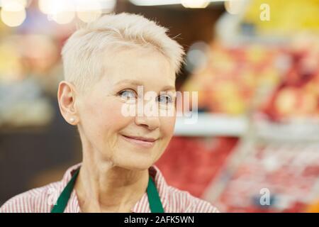 Kopf und Schultern Portrait von lächelnden älteren Frau an der Kamera schaut beim Verkauf von Obst und Gemüse bei Farmers Market, Kopie Raum Stockfoto