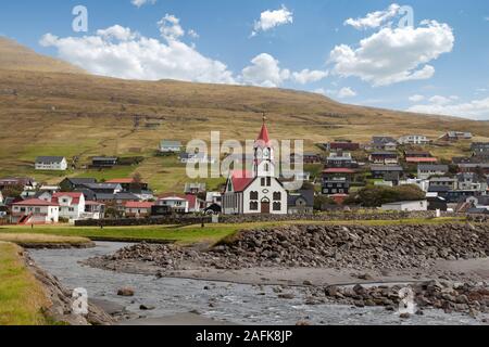 Sandavagur Kirche mit rotem Dach auch Sandavags Kirkja und den Fluss Stora im malerischen Dorf Sandavagur auf den Färöer Inseln, De Stockfoto