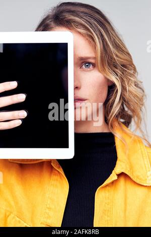 Studio Portrait von Sorgen junge Frau mit Gesicht mit digitalen Tablet Stockfoto