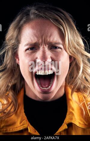 Studio Portrait von wütende Frau schrie Kamera auf schwarzem Hintergrund Stockfoto