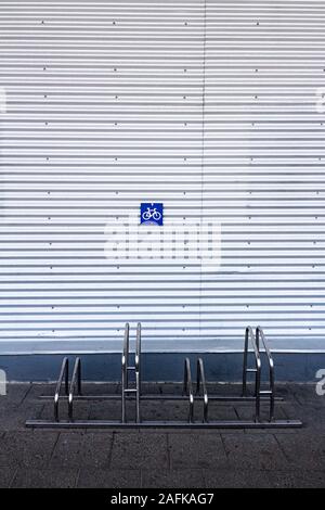 Bügeleisen Bike Rack durch die grauen Wellblech Wand Stockfoto