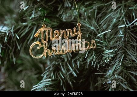 Nahaufnahme von einem goldenen englische Text "Frohe Weihnachten!" Schmuck am Weihnachtsbaum. Stockfoto