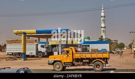 Khartum, Sudan, Ca. Februar 8., 2019: Gelbe Lkw an einer Tankstelle in der Wüste Dorf vor einer Moschee mit weißen Minarett Stockfoto