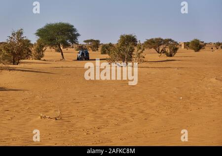 Khartum, Sudan, Ca. Februar 8., 2019: Wüste Szene mit Akazien und einem Off-Road-Fahrzeug im Schatten geparkt Stockfoto