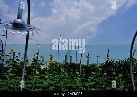 Die Ebene im Fokus fliegt bis hinter den Vordergrund mit kleinen Sonnenblumen und unscharf Metall Blumen mit Halterungen. Das Konzept der Urlaub hat gerade begonnen. Stockfoto