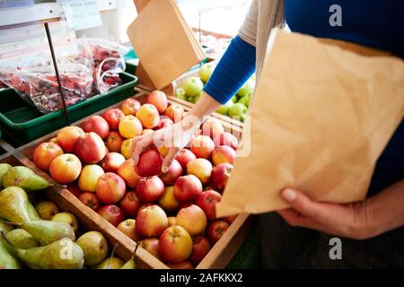 Nahaufnahme von Frau Kunde mit Papiertüte kaufen frische Äpfel in organischen Farm Shop Stockfoto