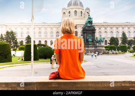 Junge weibliche Touristen auf dem Hintergrund der Maria Theresia Square in der Nähe von Museum of Natural History in Wien sitzen. Stockfoto