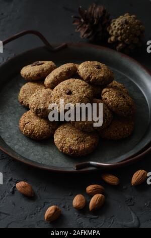 Glutenfreie gesund vegan Cookies. Haufen amond beißt in vintage Fach und ganzen Nüssen auf schwarzem Hintergrund Seitenansicht Low Key noch leben Nahaufnahme Stockfoto