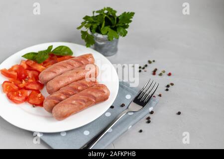 Frühstück mit Würstchen und Gemüse. Tomaten in Scheiben geschnitten. Auf einem hellen Hintergrund. Stockfoto