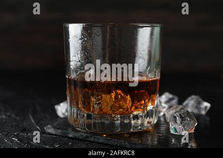 Glas Whiskey und Eiswürfel auf schwarzem Hintergrund, in der Nähe Stockfoto