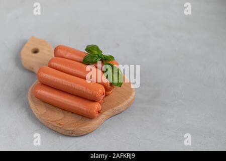 Würstchen zum Frühstück und Hot Dogs. Auf einem hellen Hintergrund. In der Nähe befinden sich Blätter Basilikum. Stockfoto