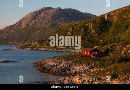 SOMMARØYA, NORWEGEN - Rote Haus auf felsigen Küste, Mitternachtssonne, Troms, Norwegen im Norden. Stockfoto