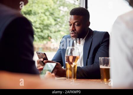 Gruppe von Kollegen alle Kontrolle Mobiltelefone während der Konferenz für Getränke in der Bar Stockfoto