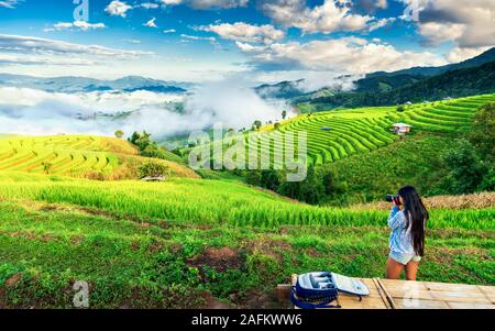 Reisermädchen machen ein Foto in der Natur und genießen bei Sonnenaufgang die Aussicht auf die Reisterrasse in Asien. Aktives Lifestyle- und Reisekonzept Stockfoto