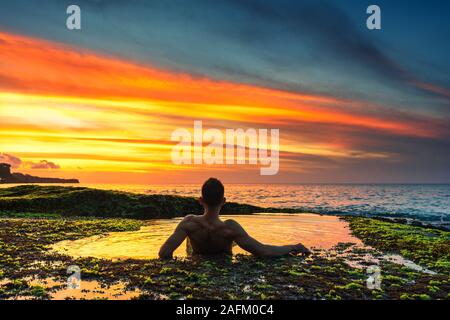 Silhouette Reisen Männer Genießen den Sonnenuntergang im Natürlichen Pool EINES Tropical Beach Stockfoto