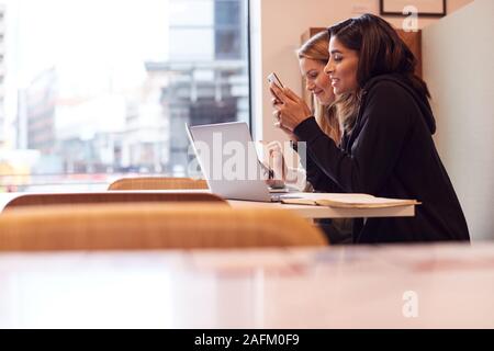 Zwei junge Unternehmerinnen, die sich für Treffen um den Tisch in der modernen offenen Arbeitsbereich Stockfoto